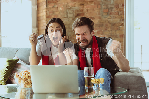 Image of Excited football fans watching sport match at home, remote support of favourite team during coronavirus pandemic outbreak