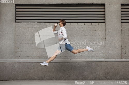 Image of Jumping young man in front of buildings, on the run in jump high