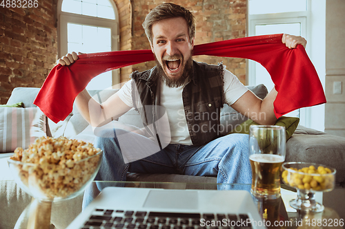 Image of Excited football fan watching sport match at home, remote support of favourite team during coronavirus pandemic outbreak