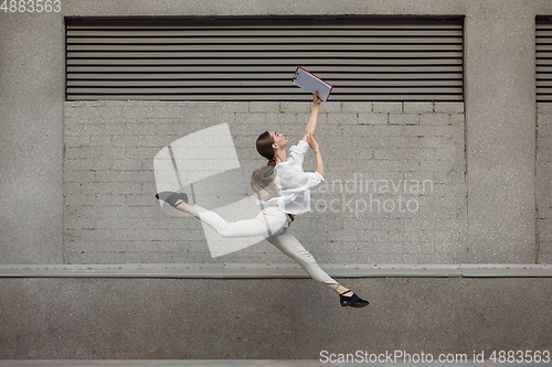 Image of Jumping young woman in front of buildings, on the run in jump high