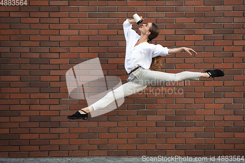 Image of Jumping young woman in front of buildings, on the run in jump high