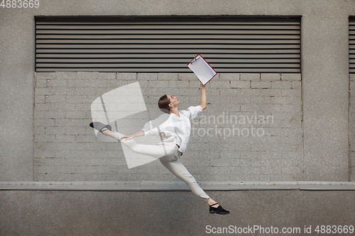 Image of Jumping young woman in front of buildings, on the run in jump high