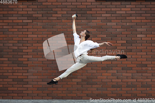 Image of Jumping young woman in front of buildings, on the run in jump high