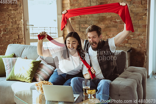 Image of Excited football fans watching sport match at home, remote support of favourite team during coronavirus pandemic outbreak