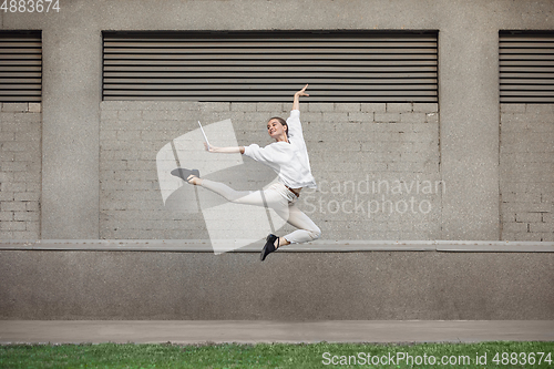 Image of Jumping young woman in front of buildings, on the run in jump high