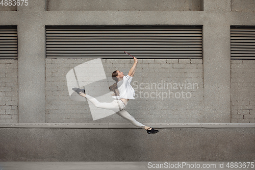 Image of Jumping young woman in front of buildings, on the run in jump high