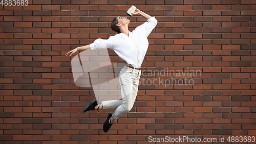 Image of Jumping young woman in front of buildings, on the run in jump high