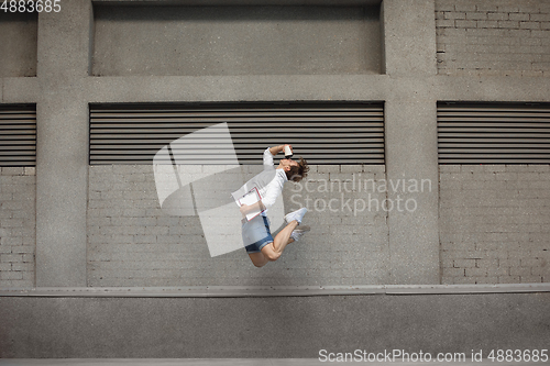 Image of Jumping young man in front of buildings, on the run in jump high