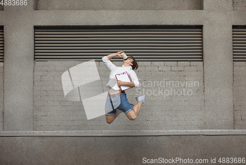 Image of Jumping young man in front of buildings, on the run in jump high