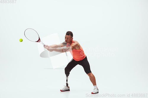 Image of Athlete with disabilities or amputee isolated on white studio background. Professional male tennis player with leg prosthesis training and practicing in studio.