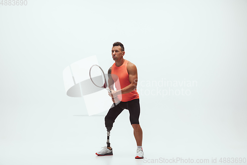 Image of Athlete with disabilities or amputee isolated on white studio background. Professional male tennis player with leg prosthesis training and practicing in studio.