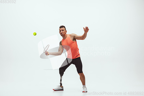 Image of Athlete with disabilities or amputee isolated on white studio background. Professional male tennis player with leg prosthesis training and practicing in studio.