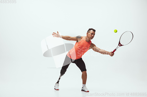 Image of Athlete with disabilities or amputee isolated on white studio background. Professional male tennis player with leg prosthesis training and practicing in studio.