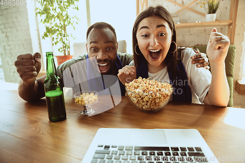 Image of Excited football fans watching sport match at home, remote support of favourite team during coronavirus pandemic outbreak