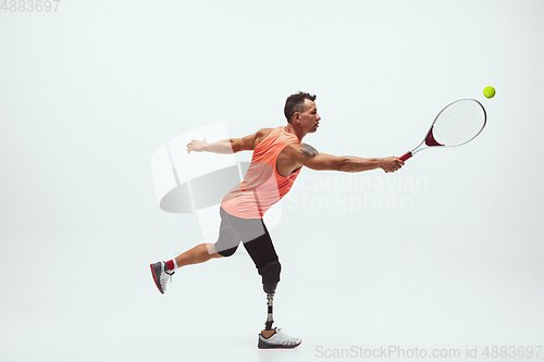 Image of Athlete with disabilities or amputee isolated on white studio background. Professional male tennis player with leg prosthesis training and practicing in studio.