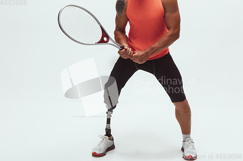 Image of Athlete with disabilities or amputee isolated on white studio background. Professional male tennis player with leg prosthesis training and practicing in studio.