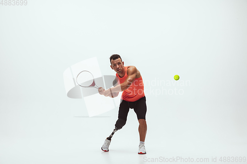 Image of Athlete with disabilities or amputee isolated on white studio background. Professional male tennis player with leg prosthesis training and practicing in studio.