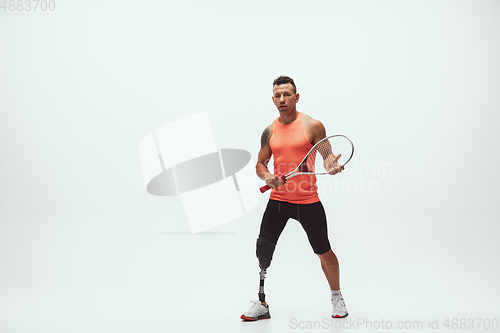 Image of Athlete with disabilities or amputee isolated on white studio background. Professional male tennis player with leg prosthesis training and practicing in studio.