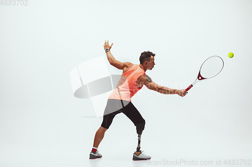 Image of Athlete with disabilities or amputee isolated on white studio background. Professional male tennis player with leg prosthesis training and practicing in studio.