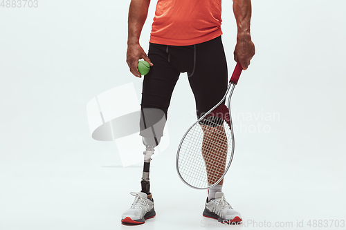 Image of Athlete with disabilities or amputee isolated on white studio background. Professional male tennis player with leg prosthesis training and practicing in studio.