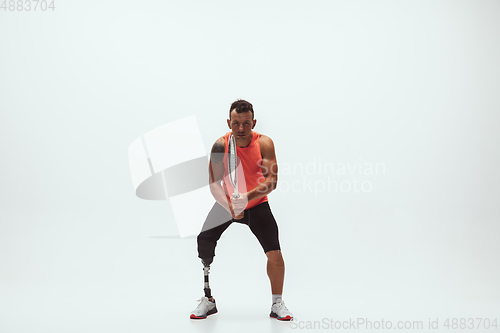 Image of Athlete with disabilities or amputee isolated on white studio background. Professional male tennis player with leg prosthesis training and practicing in studio.