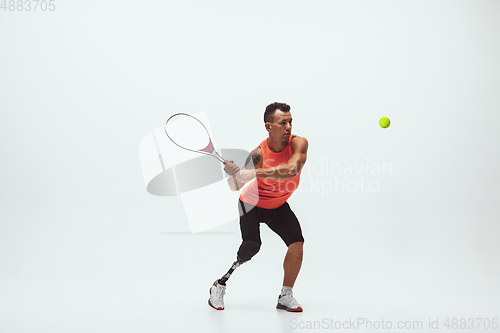 Image of Athlete with disabilities or amputee isolated on white studio background. Professional male tennis player with leg prosthesis training and practicing in studio.