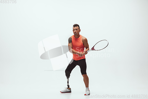 Image of Athlete with disabilities or amputee isolated on white studio background. Professional male tennis player with leg prosthesis training and practicing in studio.