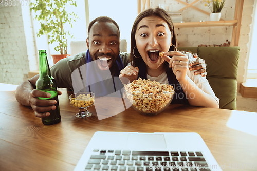 Image of Excited football fans watching sport match at home, remote support of favourite team during coronavirus pandemic outbreak