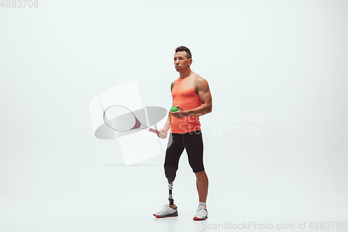 Image of Athlete with disabilities or amputee isolated on white studio background. Professional male tennis player with leg prosthesis training and practicing in studio.