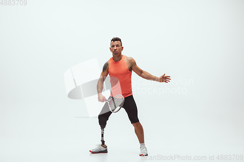 Image of Athlete with disabilities or amputee isolated on white studio background. Professional male tennis player with leg prosthesis training and practicing in studio.