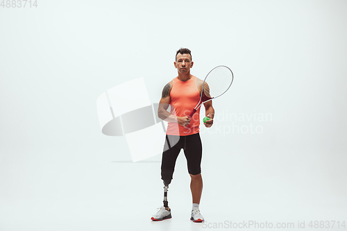 Image of Athlete with disabilities or amputee isolated on white studio background. Professional male tennis player with leg prosthesis training and practicing in studio.