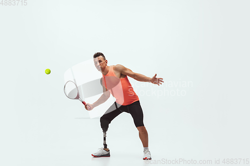 Image of Athlete with disabilities or amputee isolated on white studio background. Professional male tennis player with leg prosthesis training and practicing in studio.