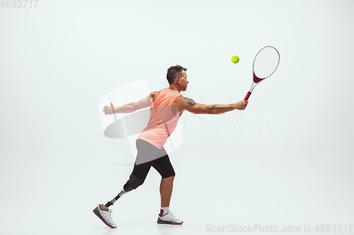 Image of Athlete with disabilities or amputee isolated on white studio background. Professional male tennis player with leg prosthesis training and practicing in studio.