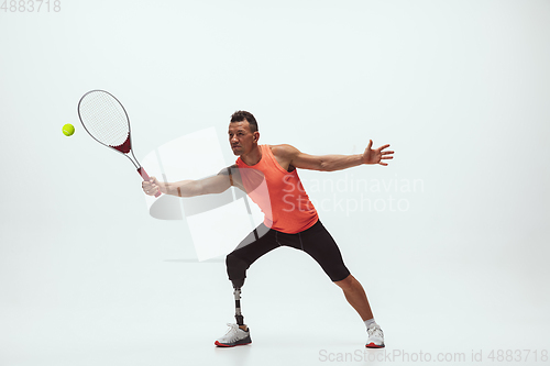 Image of Athlete with disabilities or amputee isolated on white studio background. Professional male tennis player with leg prosthesis training and practicing in studio.