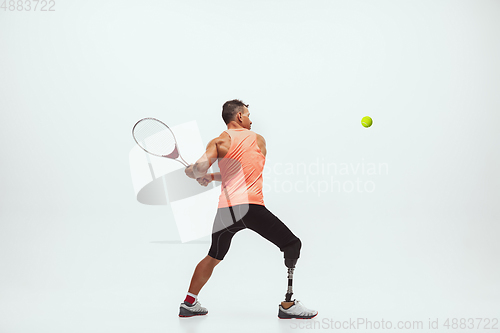 Image of Athlete with disabilities or amputee isolated on white studio background. Professional male tennis player with leg prosthesis training and practicing in studio.