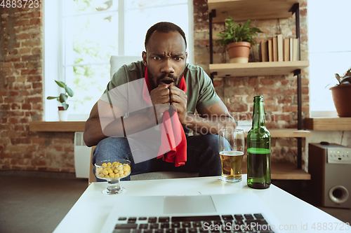 Image of Excited football fan watching sport match at home, remote support of favourite team during coronavirus pandemic outbreak