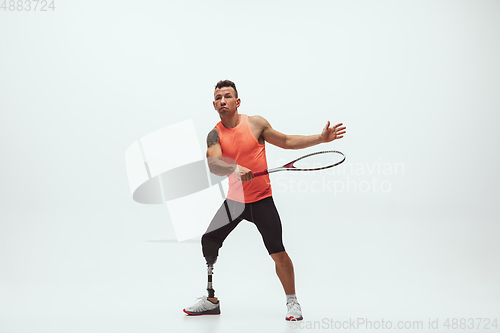 Image of Athlete with disabilities or amputee isolated on white studio background. Professional male tennis player with leg prosthesis training and practicing in studio.