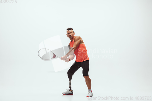 Image of Athlete with disabilities or amputee isolated on white studio background. Professional male tennis player with leg prosthesis training and practicing in studio.