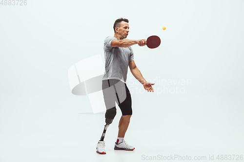 Image of Athlete with disabilities or amputee isolated on white studio background. Professional male table tennis player with leg prosthesis training and practicing in studio.