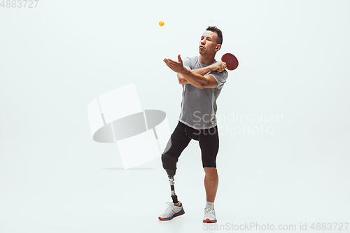 Image of Athlete with disabilities or amputee isolated on white studio background. Professional male table tennis player with leg prosthesis training and practicing in studio.