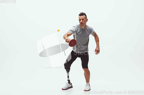 Image of Athlete with disabilities or amputee isolated on white studio background. Professional male table tennis player with leg prosthesis training and practicing in studio.