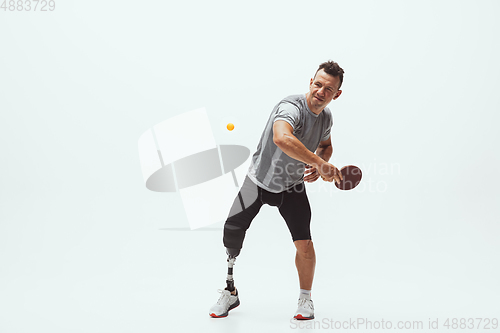 Image of Athlete with disabilities or amputee isolated on white studio background. Professional male table tennis player with leg prosthesis training and practicing in studio.