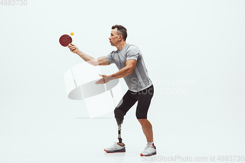 Image of Athlete with disabilities or amputee isolated on white studio background. Professional male table tennis player with leg prosthesis training and practicing in studio.