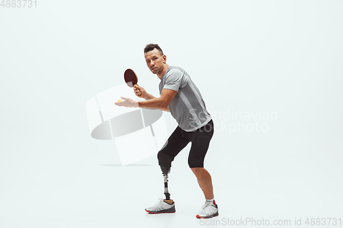 Image of Athlete with disabilities or amputee isolated on white studio background. Professional male table tennis player with leg prosthesis training and practicing in studio.