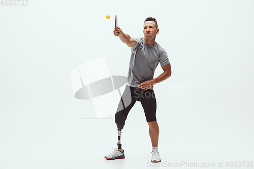 Image of Athlete with disabilities or amputee isolated on white studio background. Professional male table tennis player with leg prosthesis training and practicing in studio.