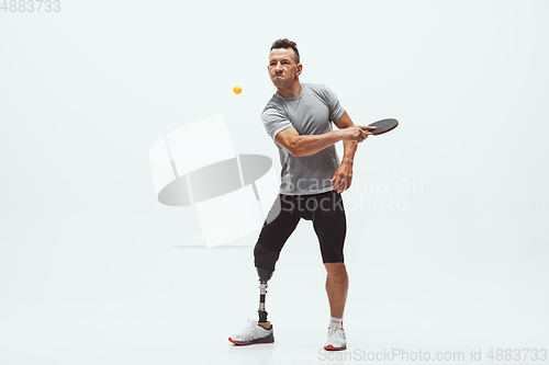 Image of Athlete with disabilities or amputee isolated on white studio background. Professional male table tennis player with leg prosthesis training and practicing in studio.