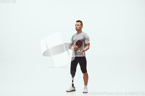 Image of Athlete with disabilities or amputee isolated on white studio background. Professional male table tennis player with leg prosthesis training and practicing in studio.