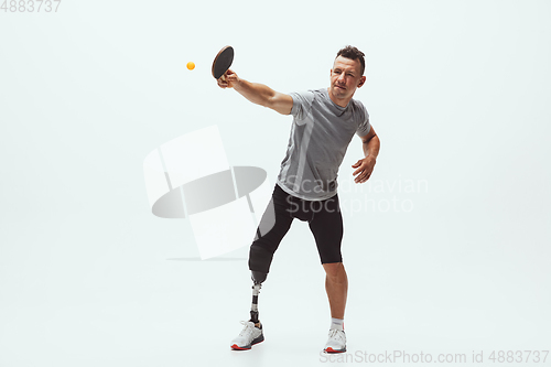 Image of Athlete with disabilities or amputee isolated on white studio background. Professional male table tennis player with leg prosthesis training and practicing in studio.