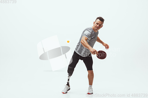 Image of Athlete with disabilities or amputee isolated on white studio background. Professional male table tennis player with leg prosthesis training and practicing in studio.