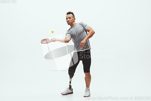 Image of Athlete with disabilities or amputee isolated on white studio background. Professional male table tennis player with leg prosthesis training and practicing in studio.